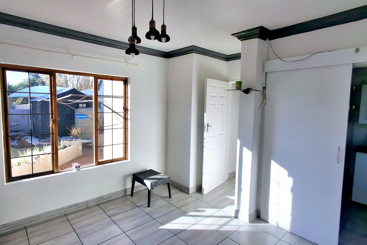 A bright, empty bedroom featuring tiled flooring, built-in storage, and an en-suite bathroom, offering a clean canvas for personalization.