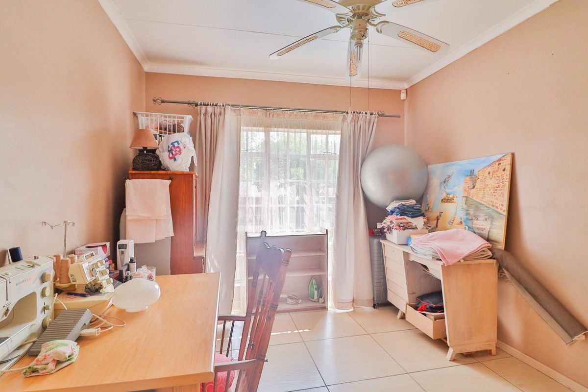 A functional bedroom featuring tiled flooring, a ceiling fan, and a sliding glass door providing natural light.
