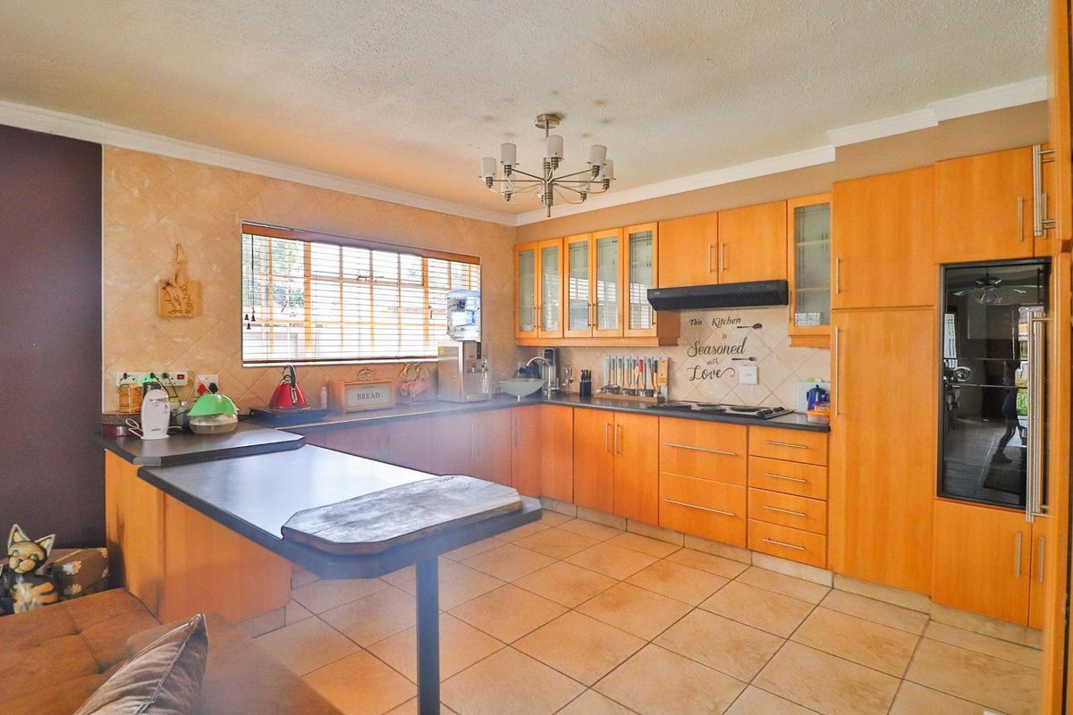 A functional kitchen featuring wood-finish cabinetry, dark countertops, tiled flooring, and a built-in oven with an extractor fan.