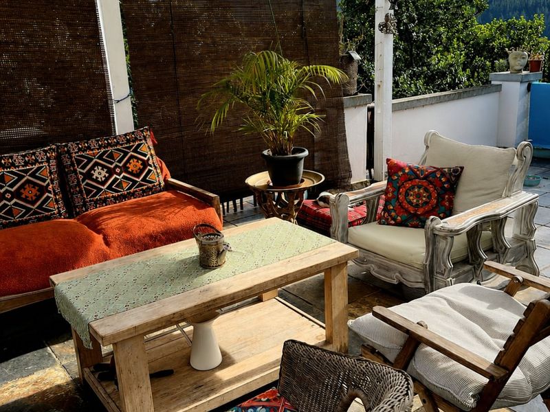 A covered outdoor patio area featuring a timber pergola structure and stone tile flooring, offering a relaxed space for outdoor living.