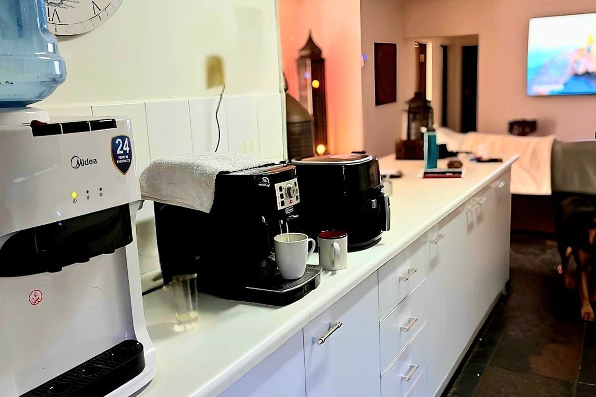 A functional kitchen area featuring white cabinetry, laminate countertops, and a tiled splashback, providing ample workspace and storage.