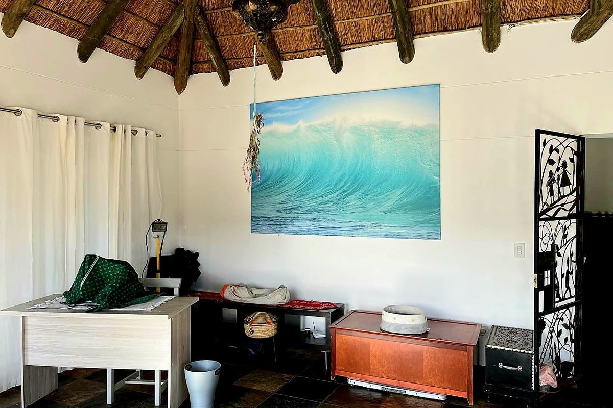 Living area featuring a traditional thatched roof with exposed timber rafters and dark slate tile flooring, creating a rustic atmosphere.