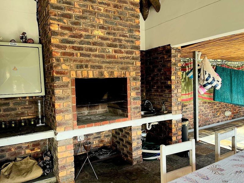 Covered outdoor patio area featuring a traditional built-in brick braai and a functional sink, ideal for outdoor entertaining and dining.