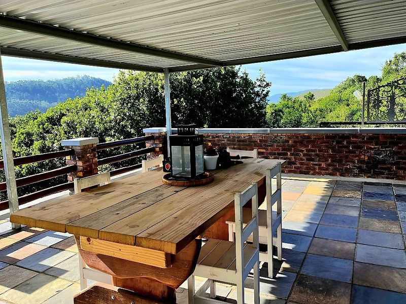 A covered outdoor patio featuring tiled flooring and a brick balustrade, offering scenic views of the surrounding landscape.