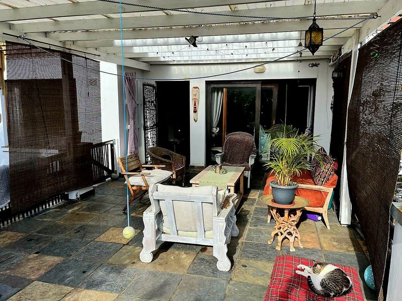 Covered patio area featuring a timber pergola structure and slate tile flooring, providing a sheltered outdoor living space with access to the main dwelling.