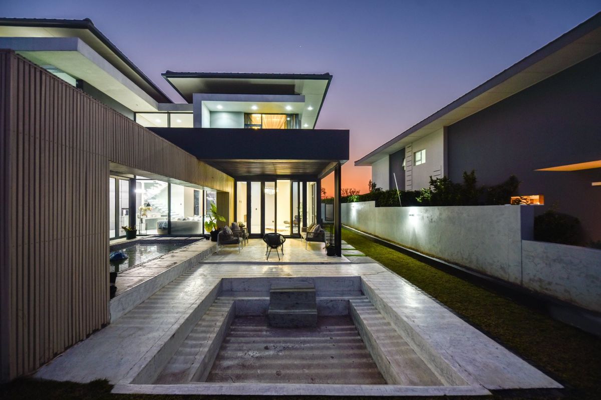 Modern architectural rear elevation featuring a covered patio, integrated swimming pool, and expansive glass sliding doors, perfect for seamless indoor-outdoor living.
