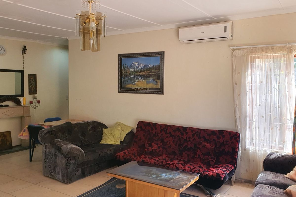 A living room featuring tiled flooring, a fireplace mantel, and a wall-mounted split-system air conditioner.