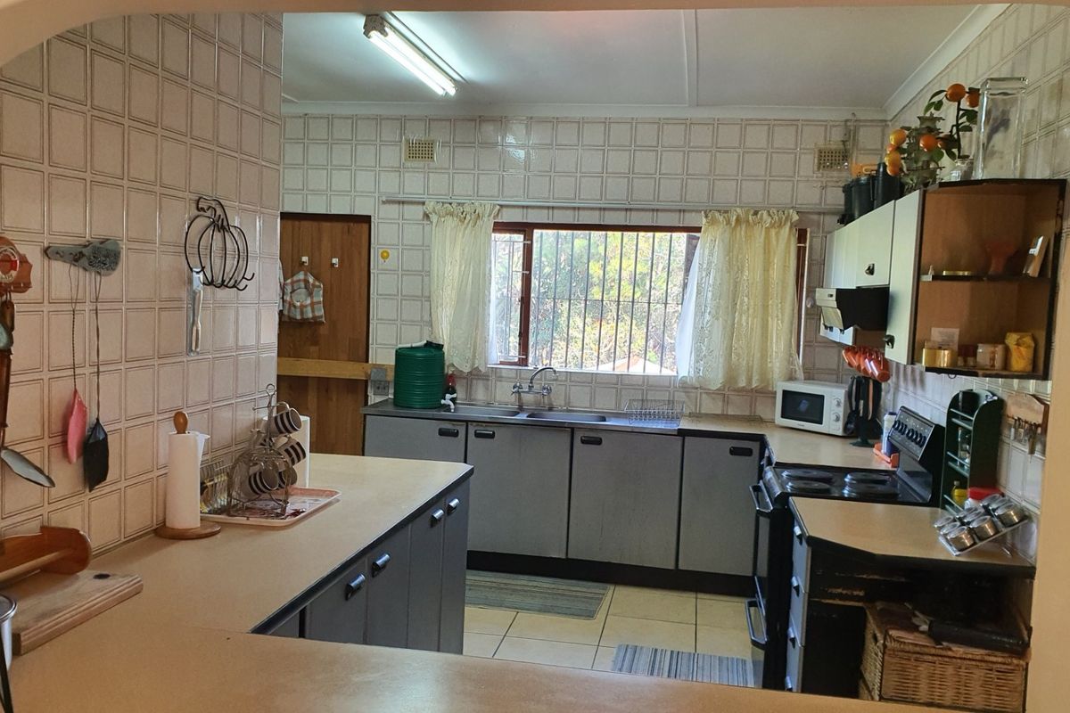 A functional kitchen featuring tiled walls, built-in cabinetry, and a double sink, offering a dated aesthetic with potential for modern renovation.