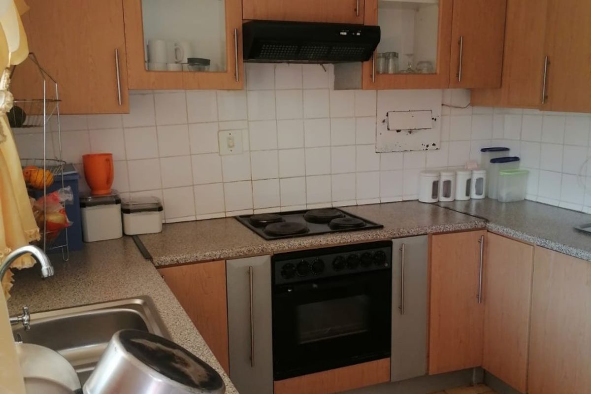 Functional kitchen featuring laminate cabinetry, built-in oven with electric hob, extractor fan, and tiled splashback with durable laminate countertops.