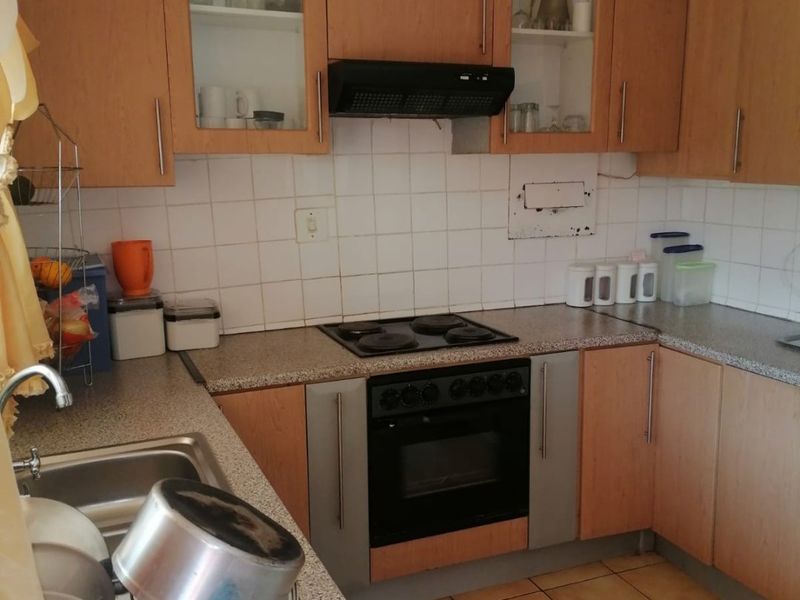 Functional kitchen featuring laminate cabinetry, built-in oven with electric hob, extractor fan, and tiled splashback with durable laminate countertops.