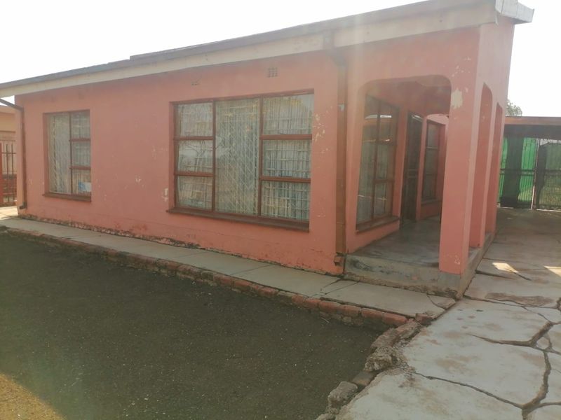 Front exterior view of a single-story house featuring a covered porch, metal security gates, and a concrete walkway with visible signs of wear.