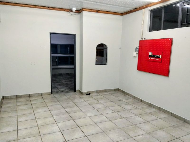 An empty utility space featuring tiled flooring, an arch window, and a wall-mounted electrical distribution board.