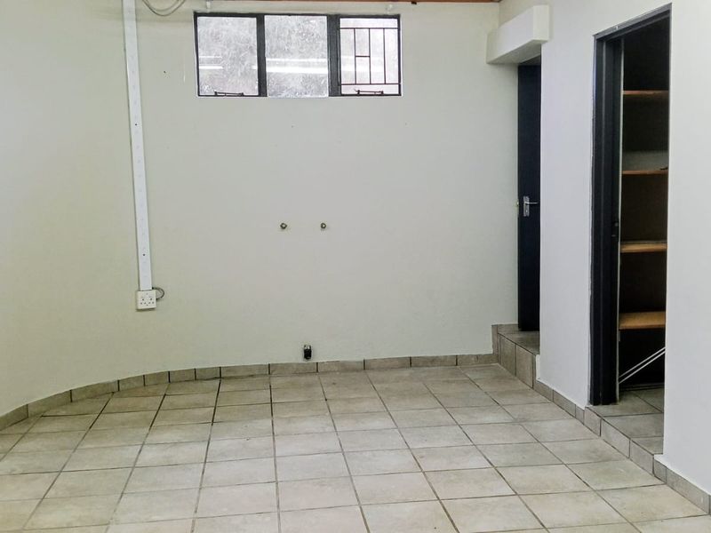 A functional, empty laundry room featuring ceramic floor tiles, built-in shelving, and dedicated plumbing and electrical connections for appliances.