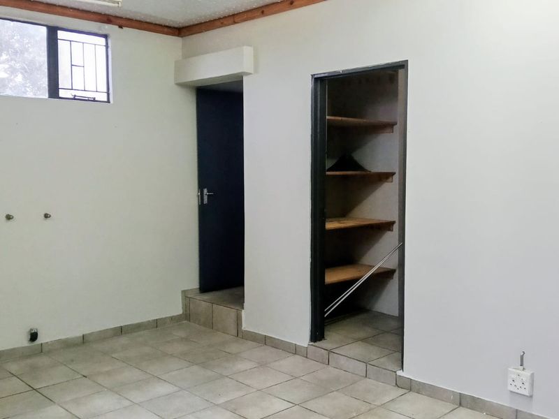 A functional laundry room featuring tiled flooring, built-in shelving, and dedicated plumbing connections for appliances.