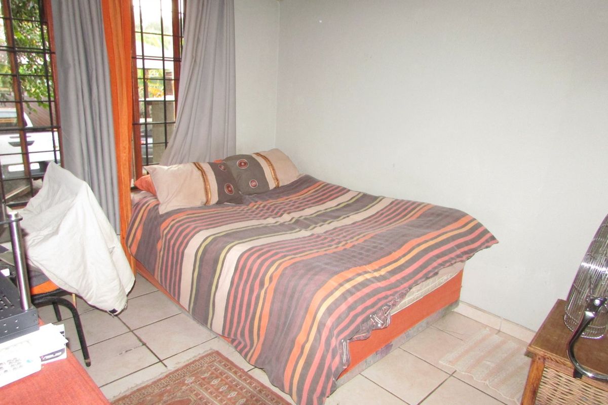 A functional bedroom featuring tiled flooring and a window fitted with security bars.