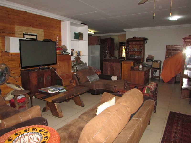 Spacious living area featuring tiled flooring, built-in shelving, and a ceiling fan, offering a versatile layout for comfortable family living.