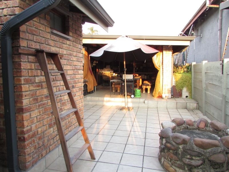 A covered outdoor patio area featuring tiled flooring, brick construction, and a stone feature, providing a functional space for outdoor living and entertainment.