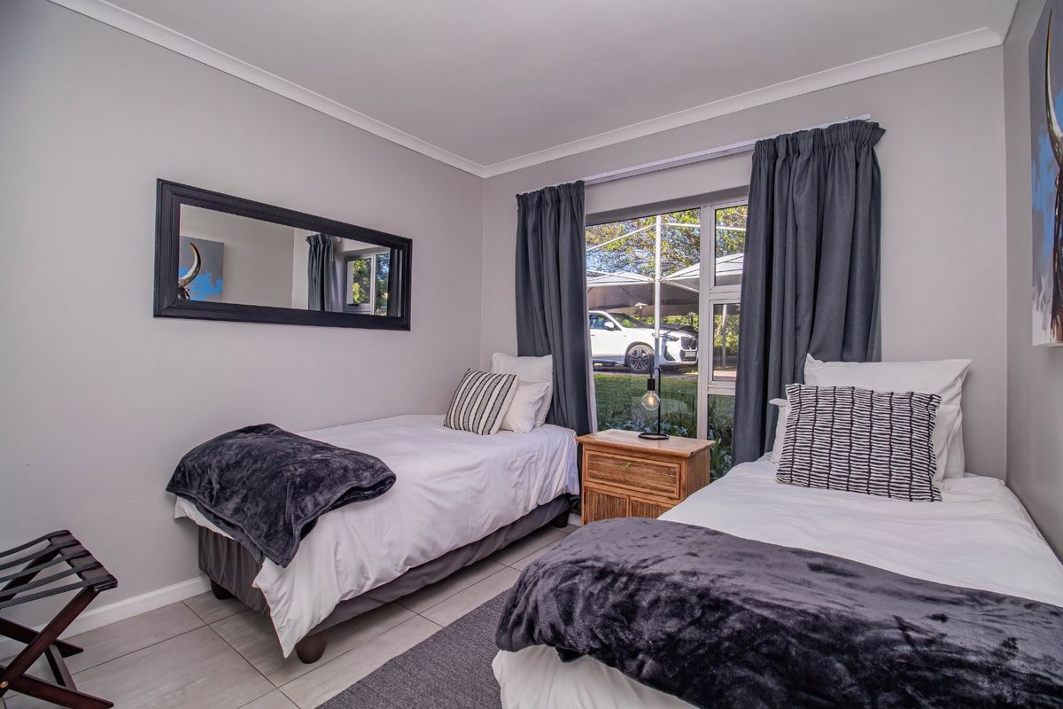 A well-maintained bedroom featuring tiled flooring, neutral wall finishes, and a large window providing natural light and exterior views.