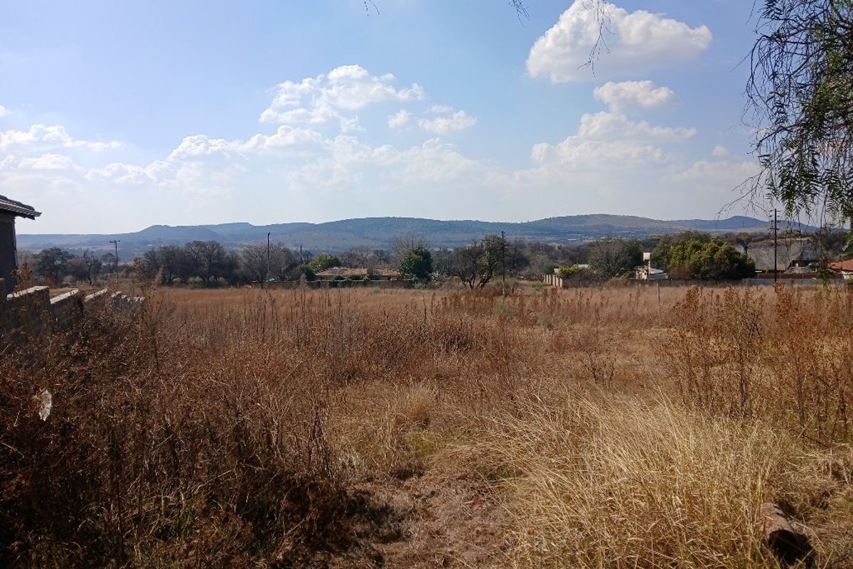 A wide-angle view of the vacant residential land, showcasing the natural landscape and distant mountain scenery.
