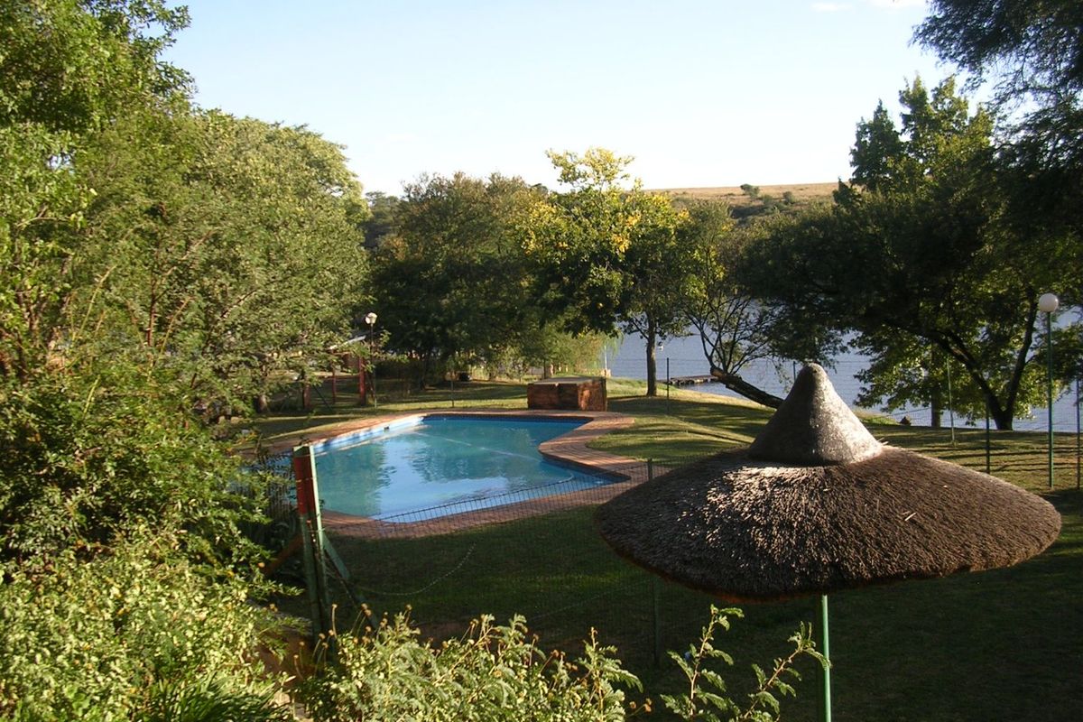 A private swimming pool set within a landscaped garden area, featuring brick coping and views towards the nearby water.