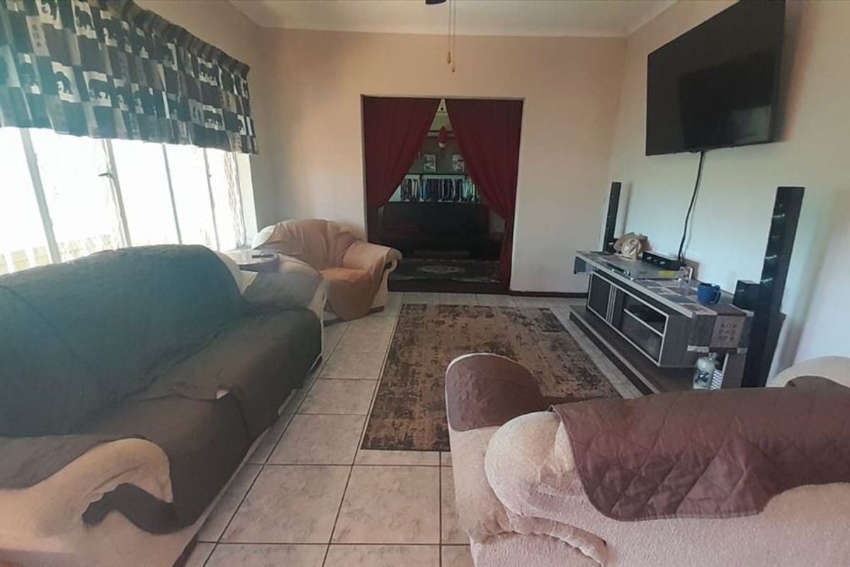 A living room featuring tiled flooring, a large window, and a ceiling fan, providing a functional space for relaxation.