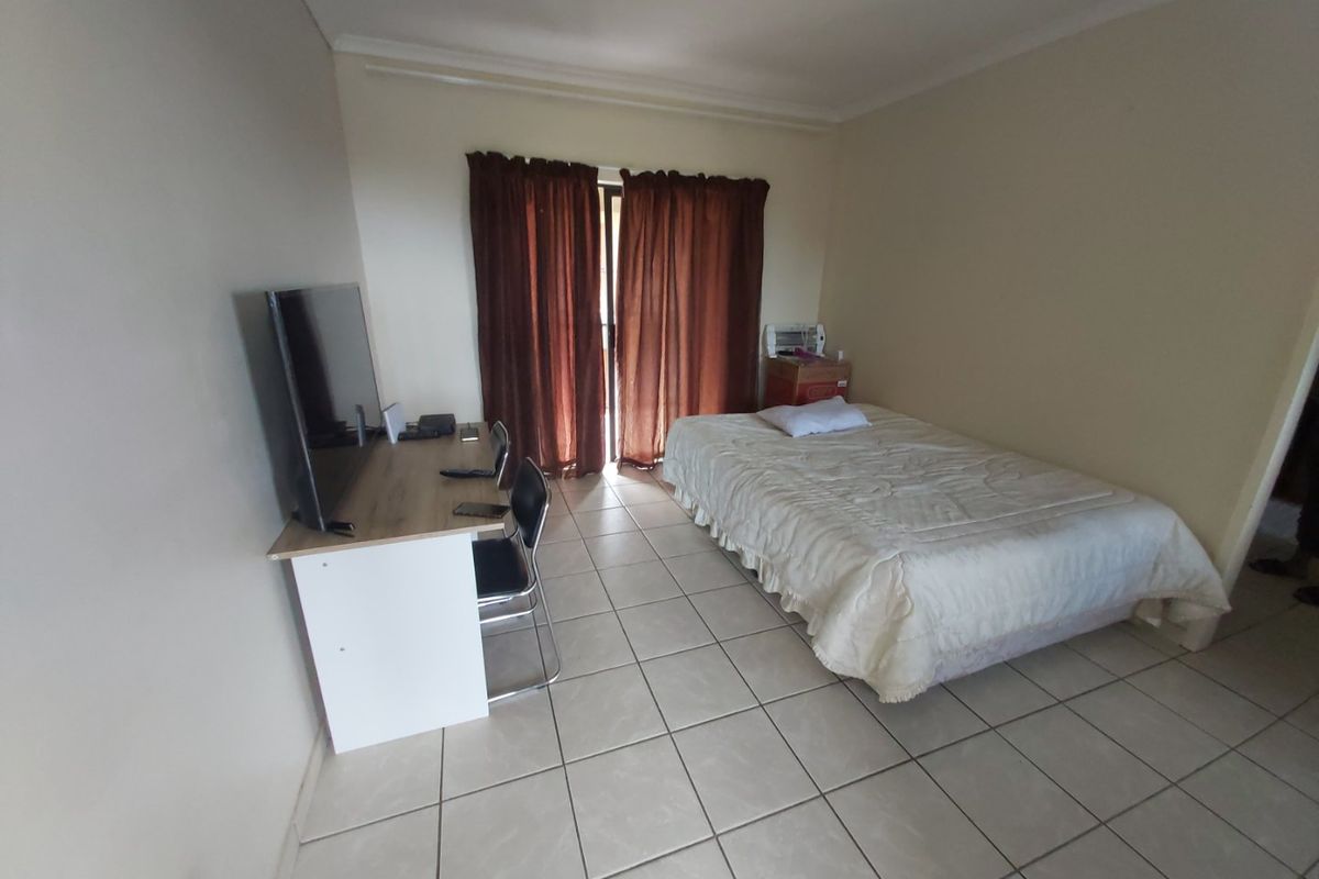 A functional bedroom featuring tiled flooring and a sliding door providing access to the exterior.