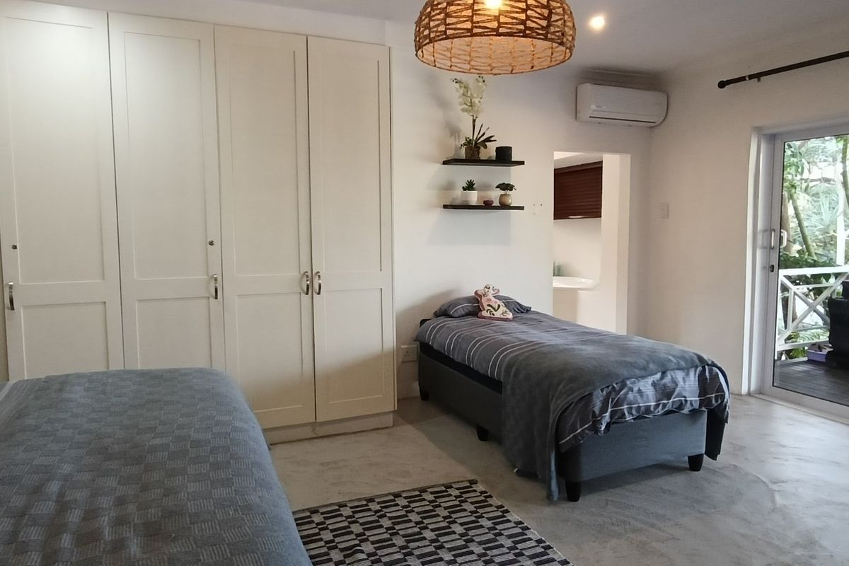 Spacious bedroom featuring extensive built-in wardrobes, polished concrete floors, and direct access to an outdoor patio through sliding glass doors.