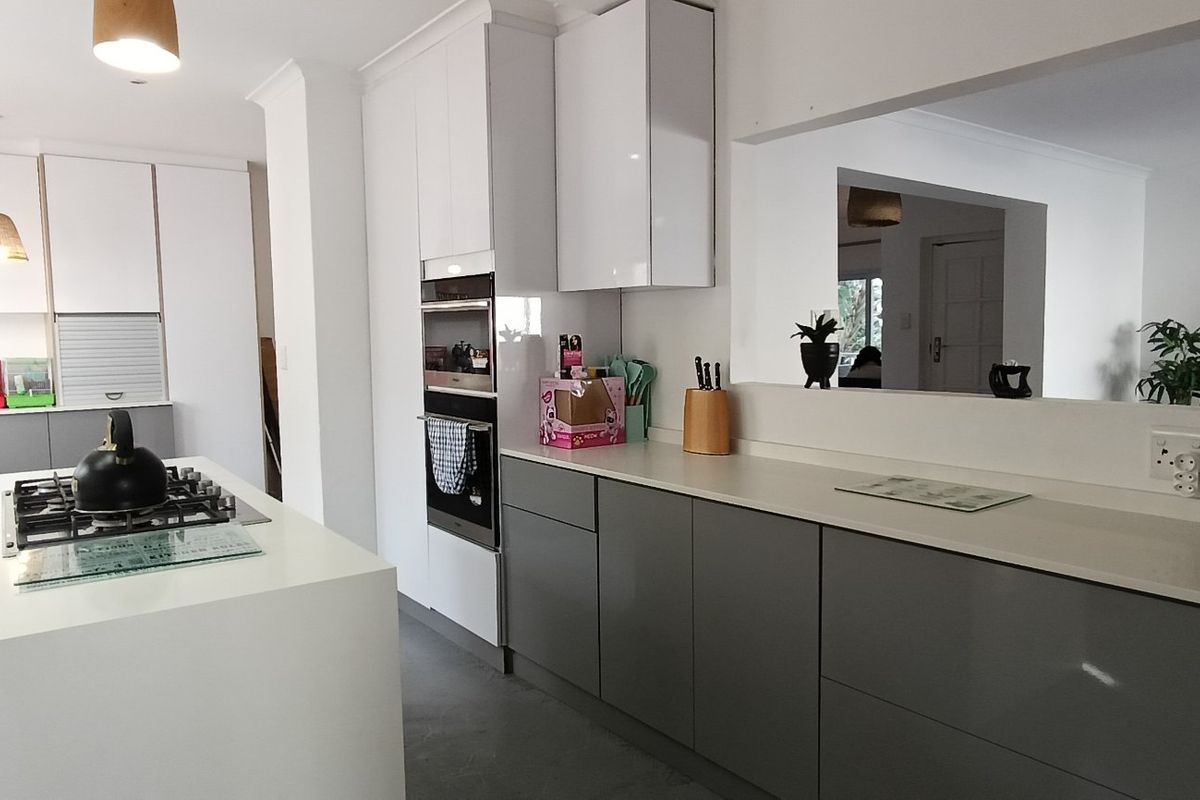 Modern kitchen featuring a central island with gas cooktop, sleek gloss cabinetry, built-in appliances, and quartz countertops, offering a clean and functional workspace.