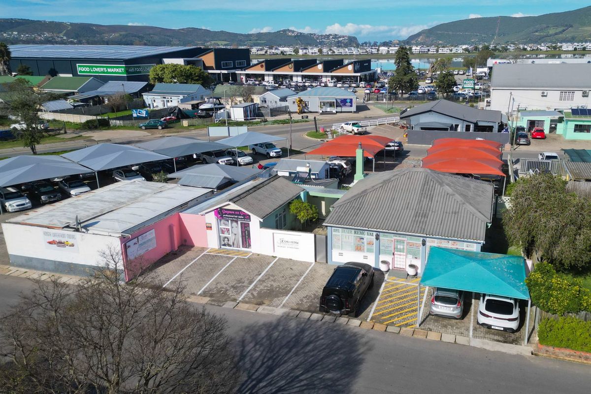 Aerial view of a commercial property featuring multiple parking bays with shade cloth carports and established building structures.