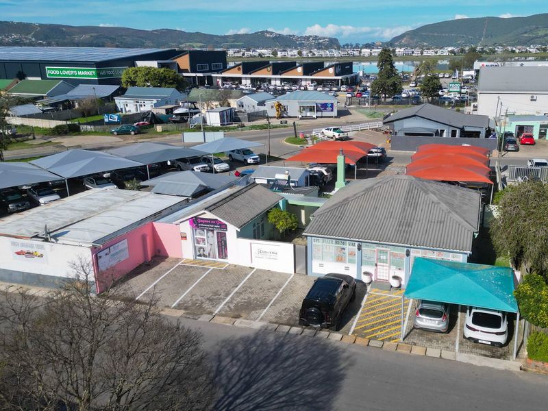 Aerial view of a commercial property featuring multiple parking bays with shade cloth carports and established building structures.