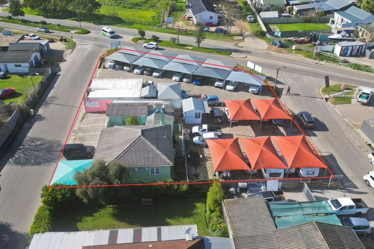 Aerial view of a commercial property featuring extensive paved parking with multiple shade cloth carports and a main building structure.