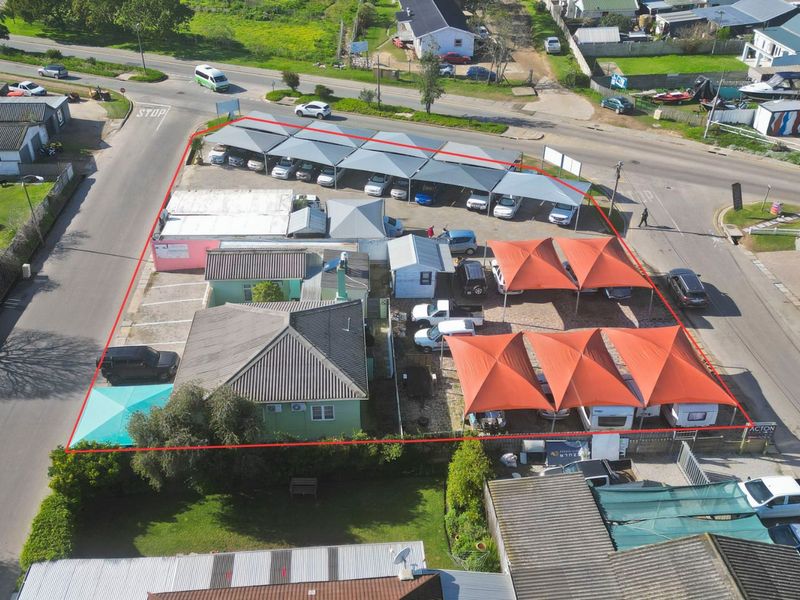 Aerial view of a commercial property featuring extensive paved parking with multiple shade cloth carports and a main building structure.