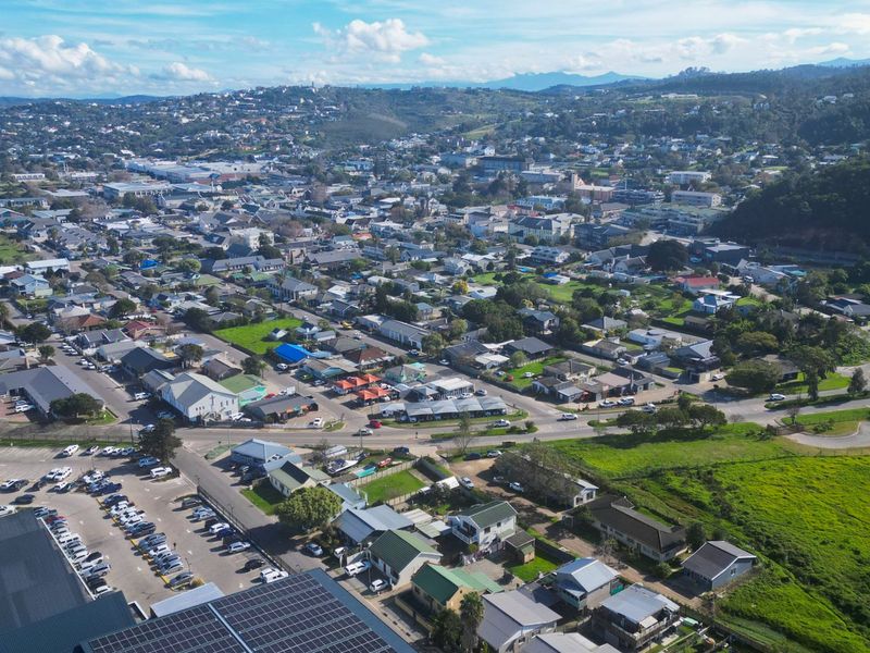 An elevated aerial view of the surrounding commercial and residential neighborhood, featuring local infrastructure, road access, and nearby parking facilities.