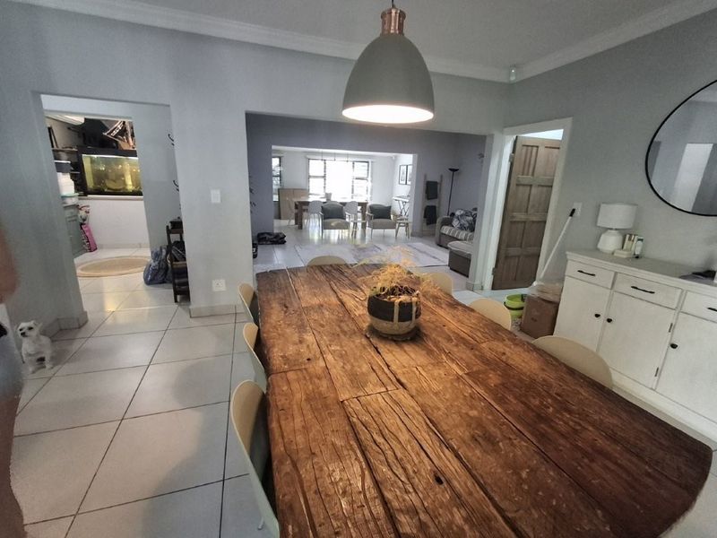 Spacious open-plan dining area featuring tiled flooring, modern pendant lighting, and seamless flow into the adjacent living and utility spaces.