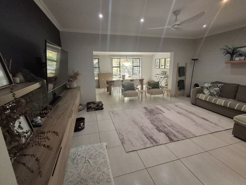 Spacious open-plan living and dining area featuring neutral tiled flooring, recessed lighting, a ceiling fan, and a built-in media console.