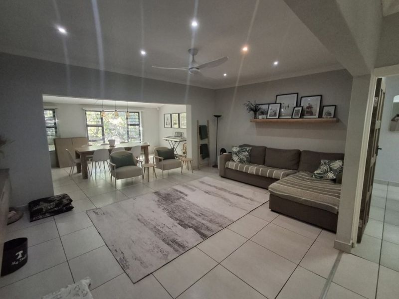 Spacious open-plan living and dining area featuring neutral tiled flooring, recessed downlighting, and a modern ceiling fan.