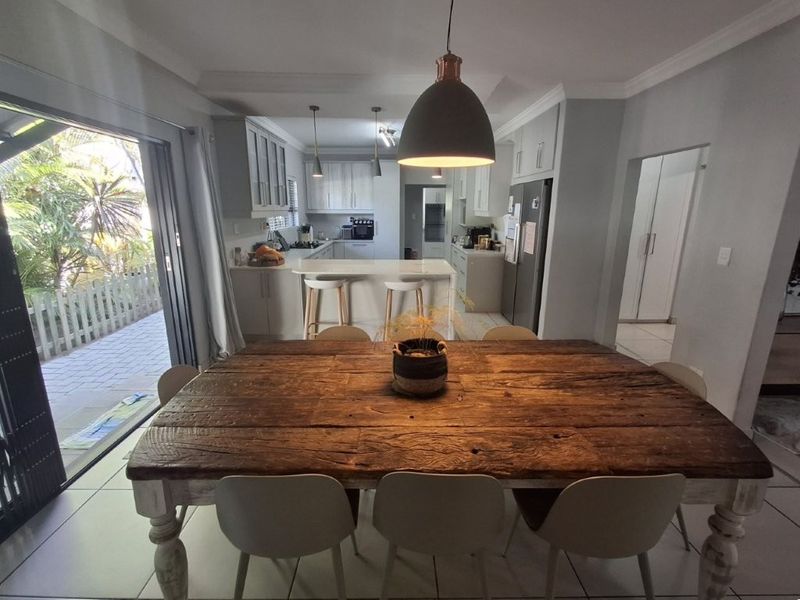 Open-plan dining and kitchen area featuring a central island, modern cabinetry, and large sliding doors providing seamless access to the outdoor patio.