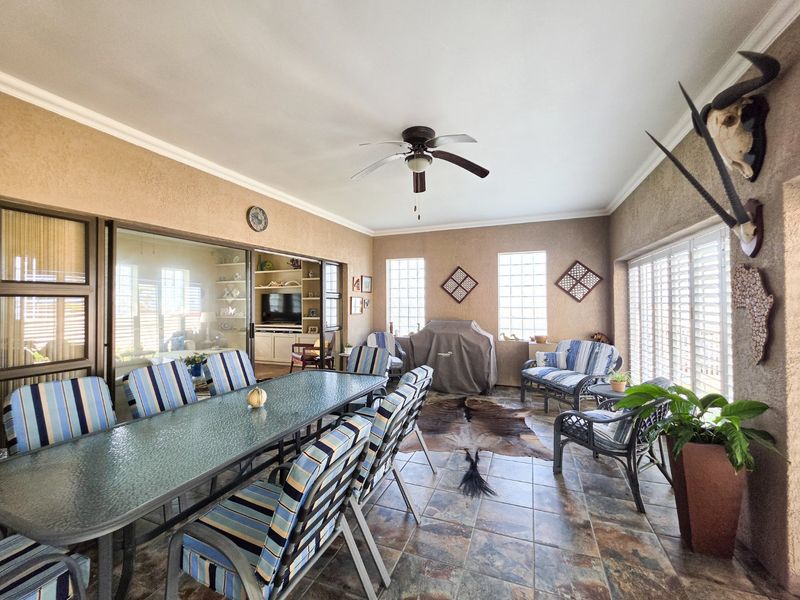 Spacious covered patio featuring tiled flooring, ceiling fan, glass block windows, and large sliding doors providing seamless access to the interior living area.
