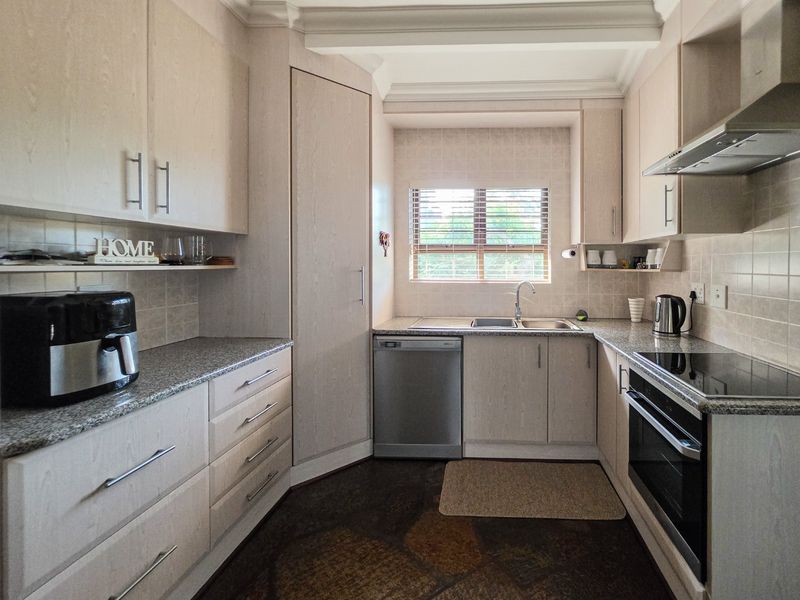 A functional kitchen featuring light-toned cabinetry, granite countertops, integrated appliances, and a tiled backsplash, offering a clean and practical workspace.