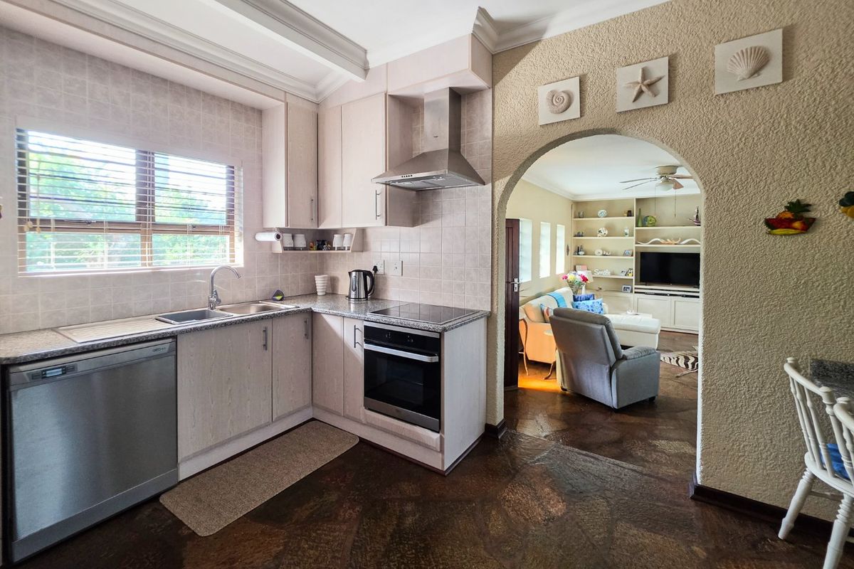 A functional kitchen featuring built-in cabinetry, granite countertops, and integrated appliances, connected to the living area through a classic arched doorway.