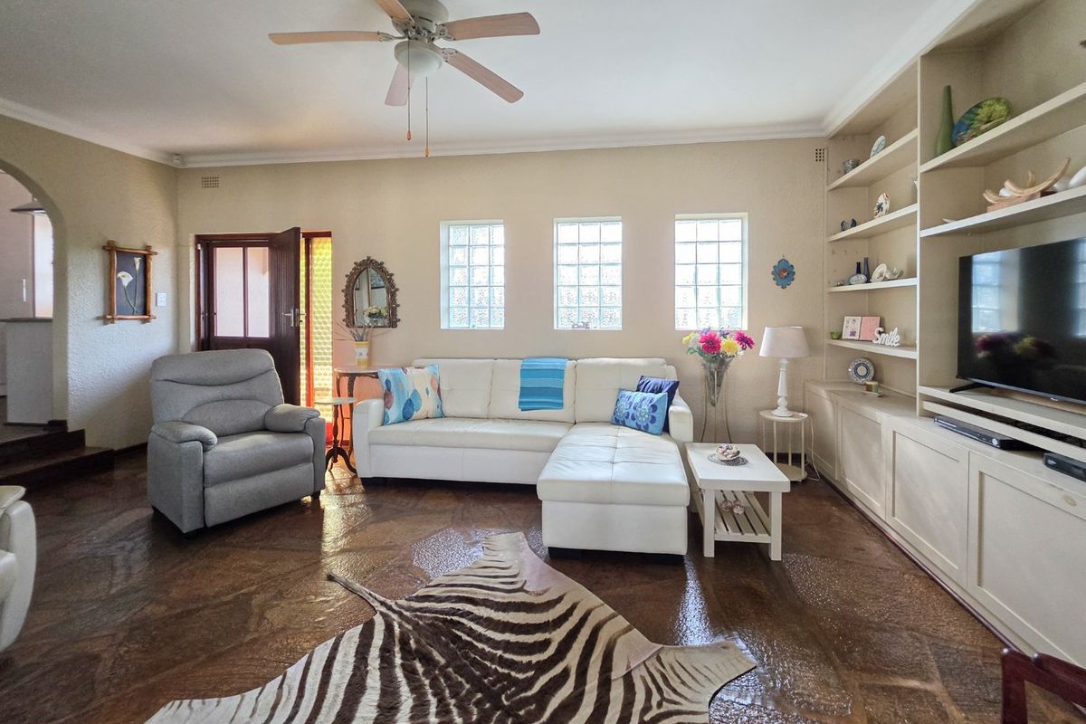 Spacious living room featuring unique stone flooring, built-in cabinetry, and natural light provided by glass block windows.