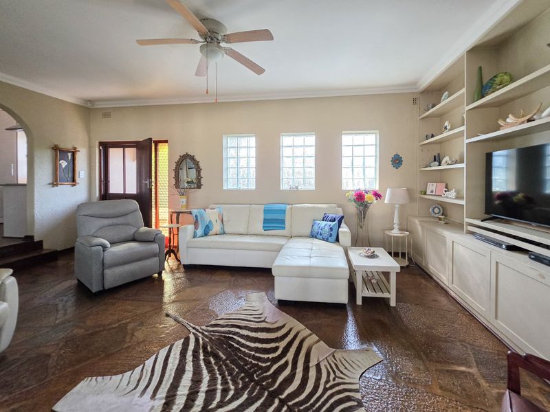 Spacious living room featuring unique stone flooring, built-in cabinetry, and natural light provided by glass block windows.