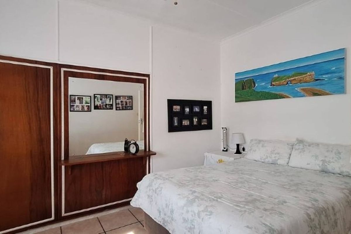 A bedroom featuring built-in wooden cabinetry with an integrated mirror and tiled flooring, offering a functional space with potential for cosmetic updates.