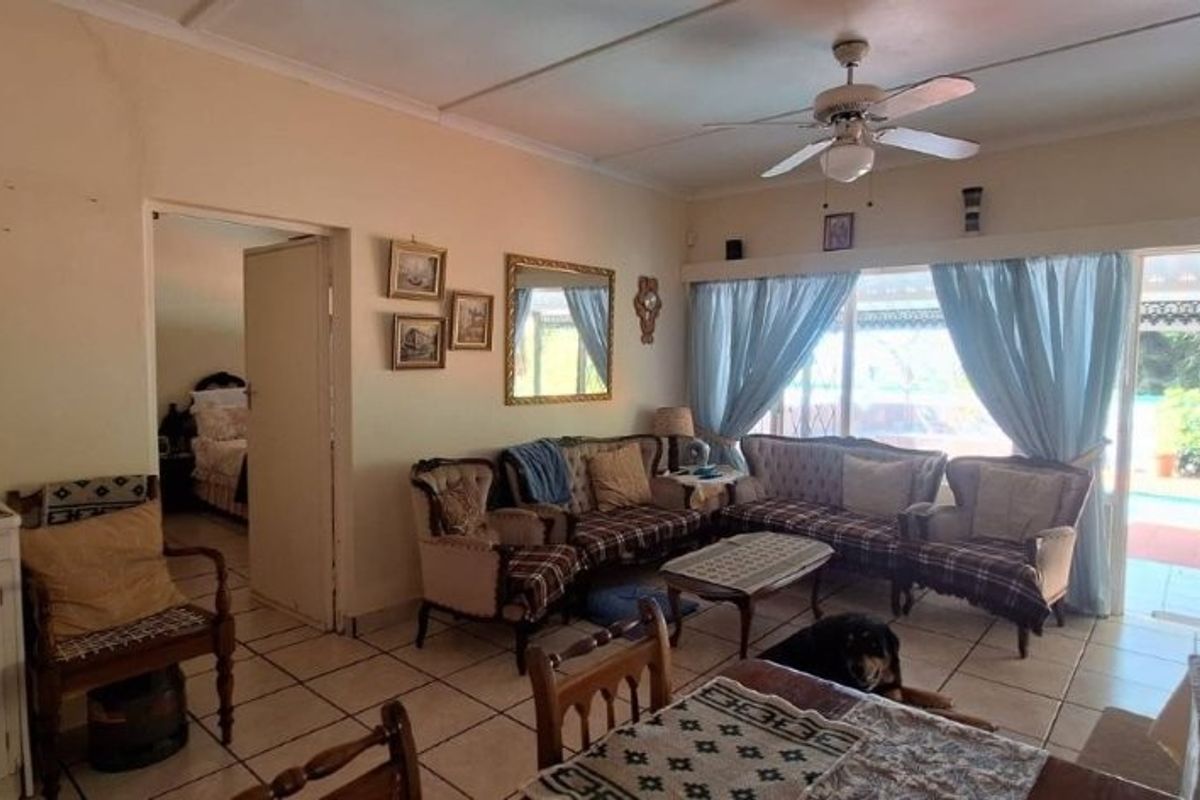 A living room featuring tiled flooring, a ceiling fan, and sliding glass doors that provide access to the outdoor pool area.