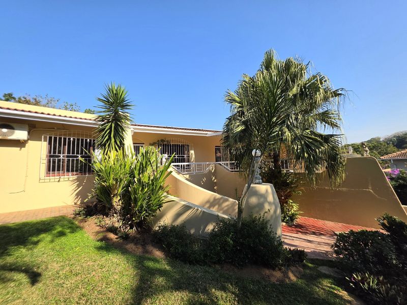 Rear exterior view of the house featuring a paved patio area, security bars on windows, and an installed air conditioning unit.