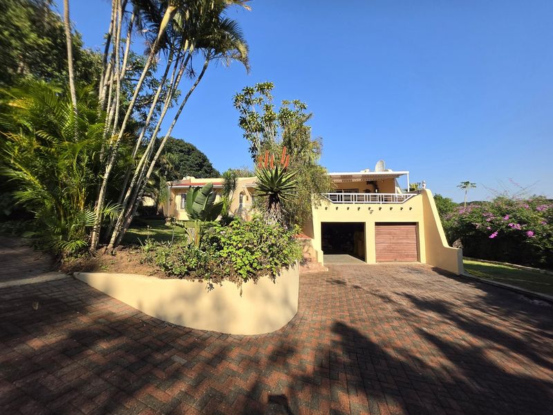 Front elevation of a residential property featuring a paved driveway, double garage, and an elevated balcony with metal balustrades.