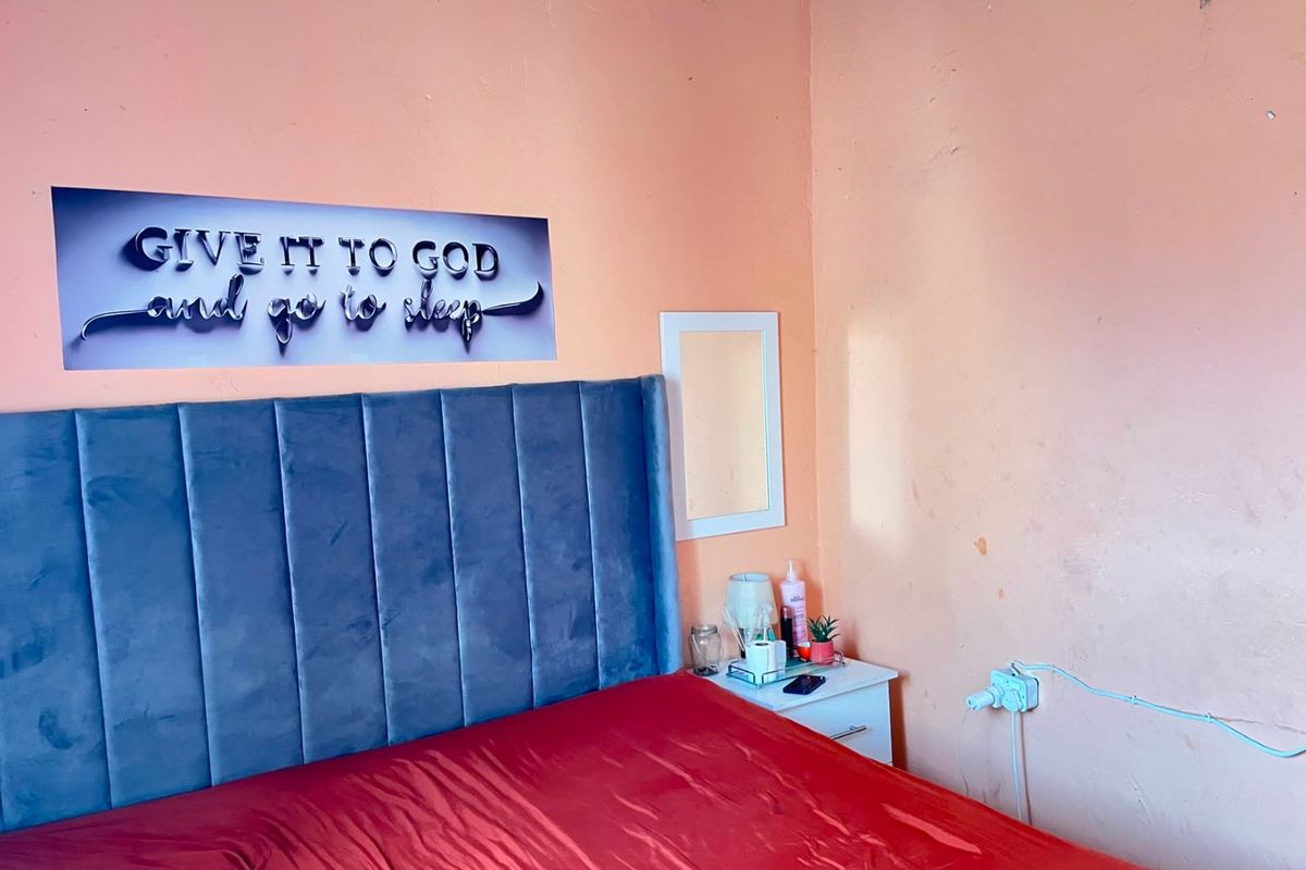 A bedroom featuring peach-toned walls and a built-in electrical outlet, requiring cosmetic updates to improve the overall finish and aesthetic appeal.