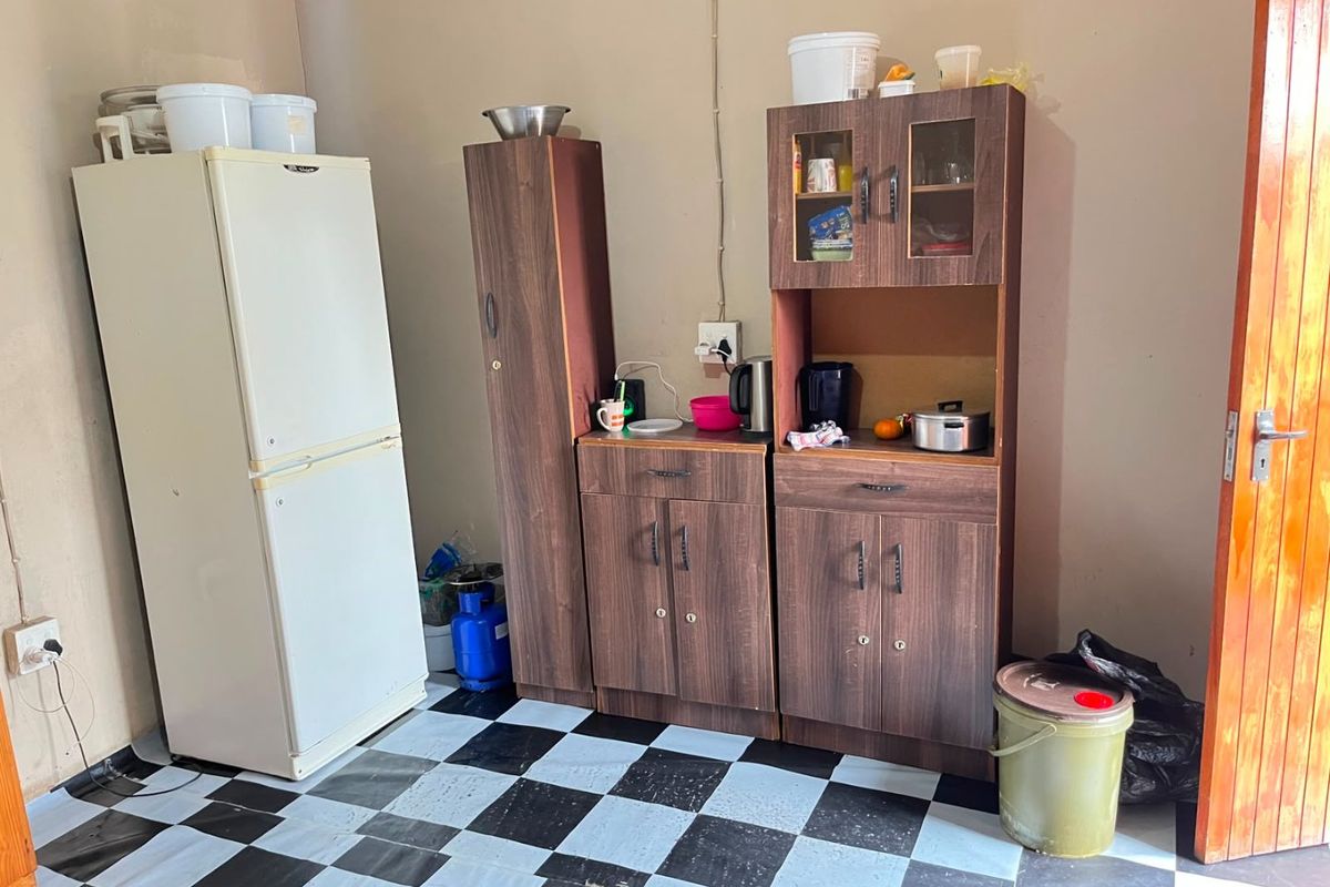 A basic kitchen area featuring dark wood-look cabinetry and checkered flooring, requiring cosmetic updates and finishing to improve functionality and aesthetic appeal.