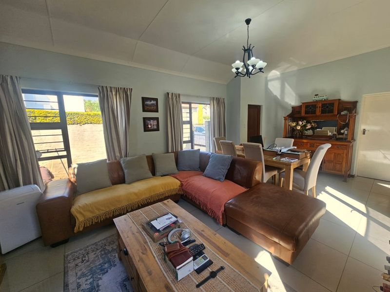 Spacious open-plan living and dining area featuring vaulted ceilings, tiled flooring, and large sliding glass doors that provide ample natural light.