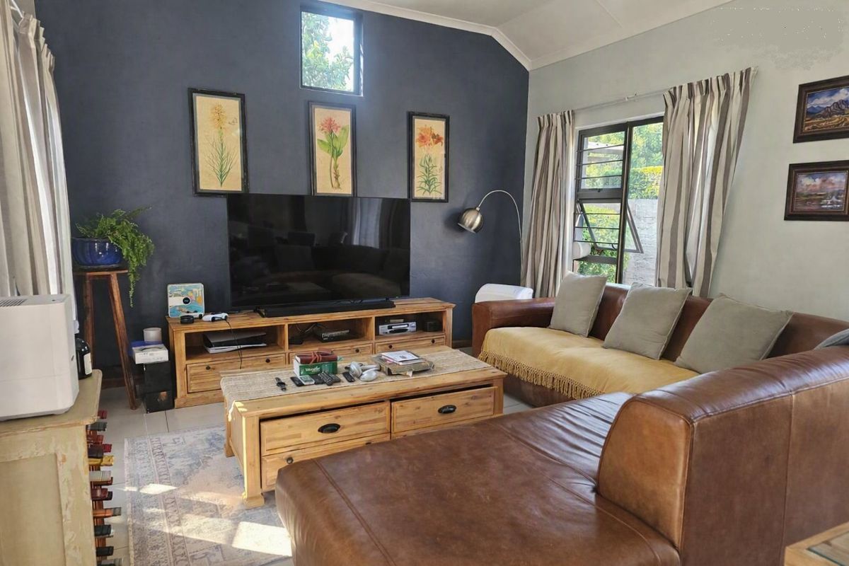 A comfortable living room featuring a vaulted ceiling, tiled flooring, and large windows that provide natural light.